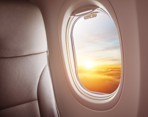 Wall Mural - airplane interior with window view of sunset above clouds.