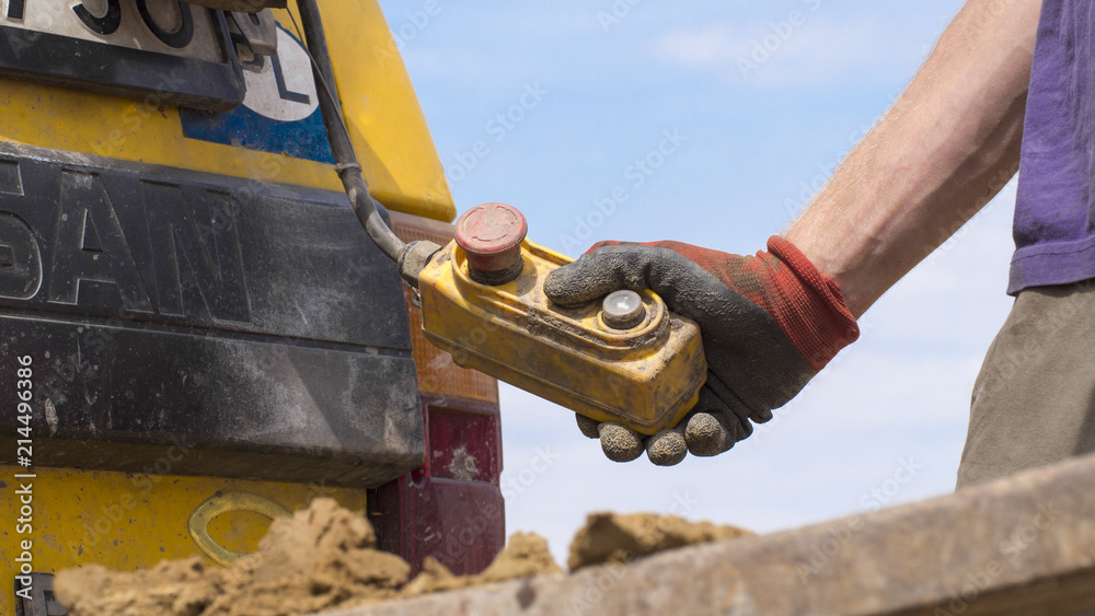 Geotechnical investigation - a hand holding a crane control button - obrazy, fototapety, plakaty 