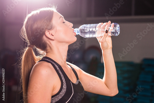 Fotografia Fitness young woman drinking water in the gym