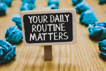 Handwriting text writing Your Daily Routine Matters.. Concept meaning Have good habits to live a healthy life Stand blackboard with white words behind blurry blue paper lobs woody floor.