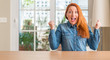 © Krakenimages.com - Redhead woman at home celebrating surprised and amazed for success with arms raised and open eyes. Winner concept.