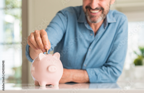 Fotografía Middle age man save money on piggy bank with a happy face standing and smiling w