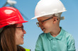 Close-up of a positive young mother engineer and son in a helmet and glasses looking at each other. Concept of future development of energy and succession of generations