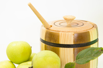 Wooden can with honey, green apples and leafs. (White background)