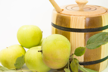 Wooden can with honey, green apples and leafs. (White background)