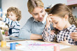 © Seventyfour - Young mother sitting at the table and supporting her daughter in her hobby to draw
