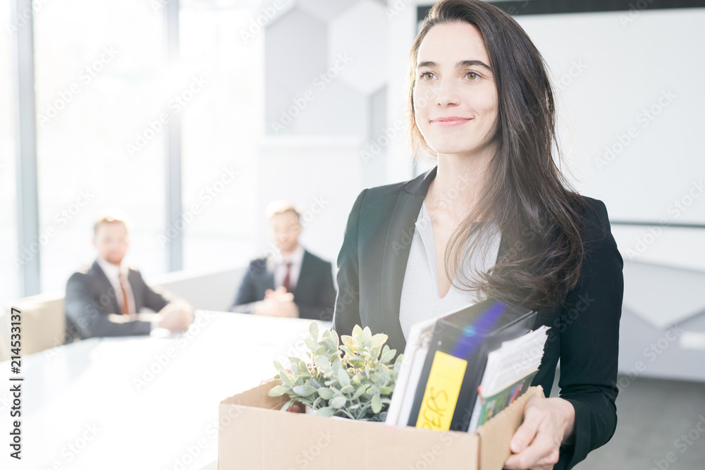 Waist up portrait of smiling young businesswoman holding box of personal belongings  leaving office after quitting job, copy space - obrazy, fototapety, plakaty 