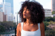 Black woman with frizzy hair looking away. Hopeful girl in the city during summer period.