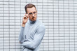 © Artem Malov - Hipster wearing glasses, standing near the wall made of small tiles