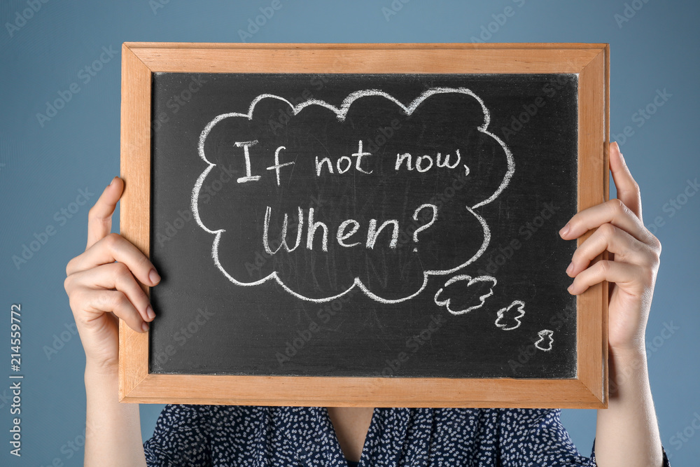 Woman holding chalkboard with phrase "If not now. When?" on color background. Time management concept