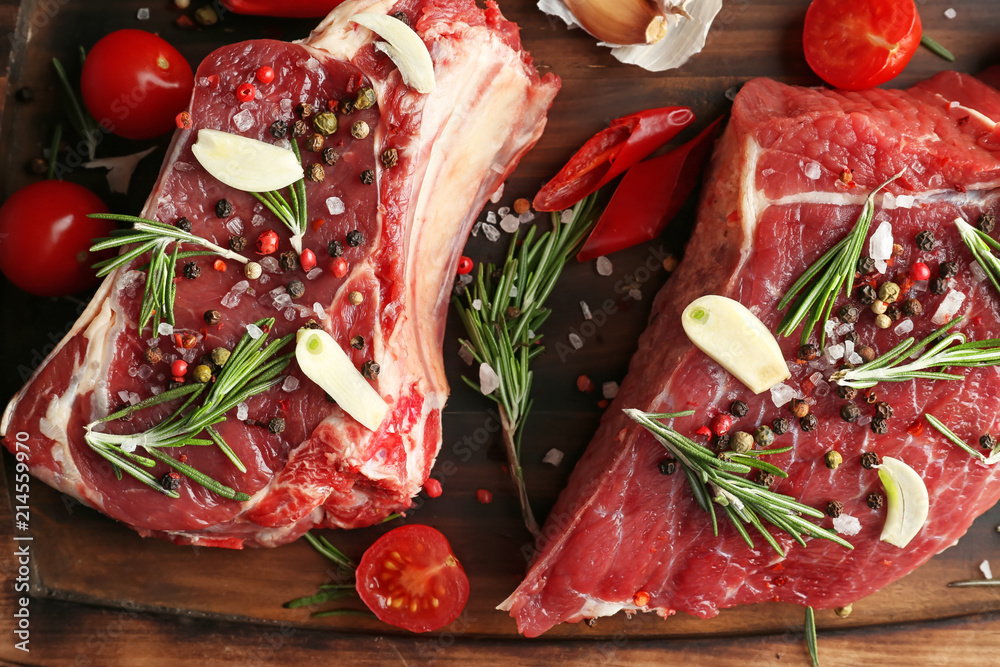 Raw meat with spices and vegetables on wooden board, closeup