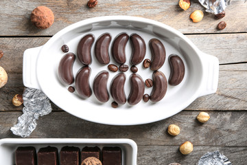 Dish with delicious chocolate candies on wooden table