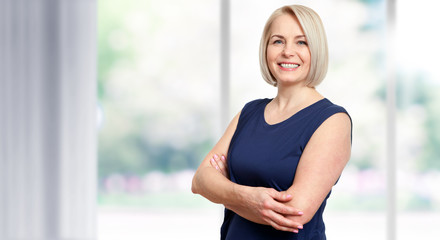 Wall Mural - attractive middle aged woman with a beautiful smile near the window.