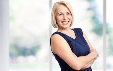 Wall Mural - attractive middle aged woman with a beautiful smile near the window.
