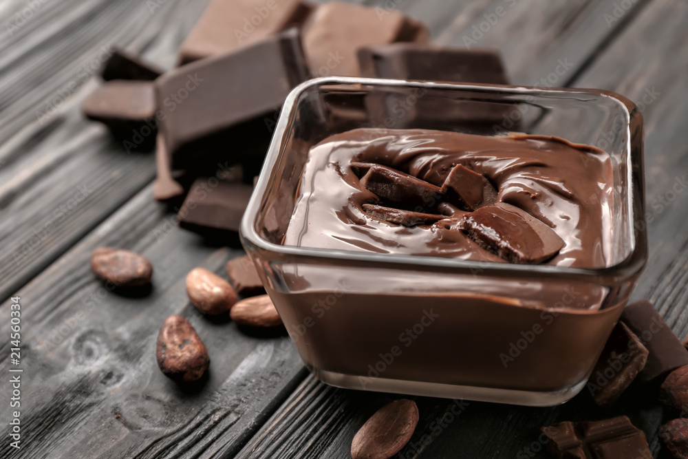 Glass bowl with molten chocolate on wooden table