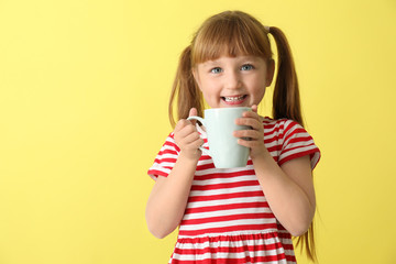 Wall Mural - Cute little girl with cup of hot cocoa drink on color background