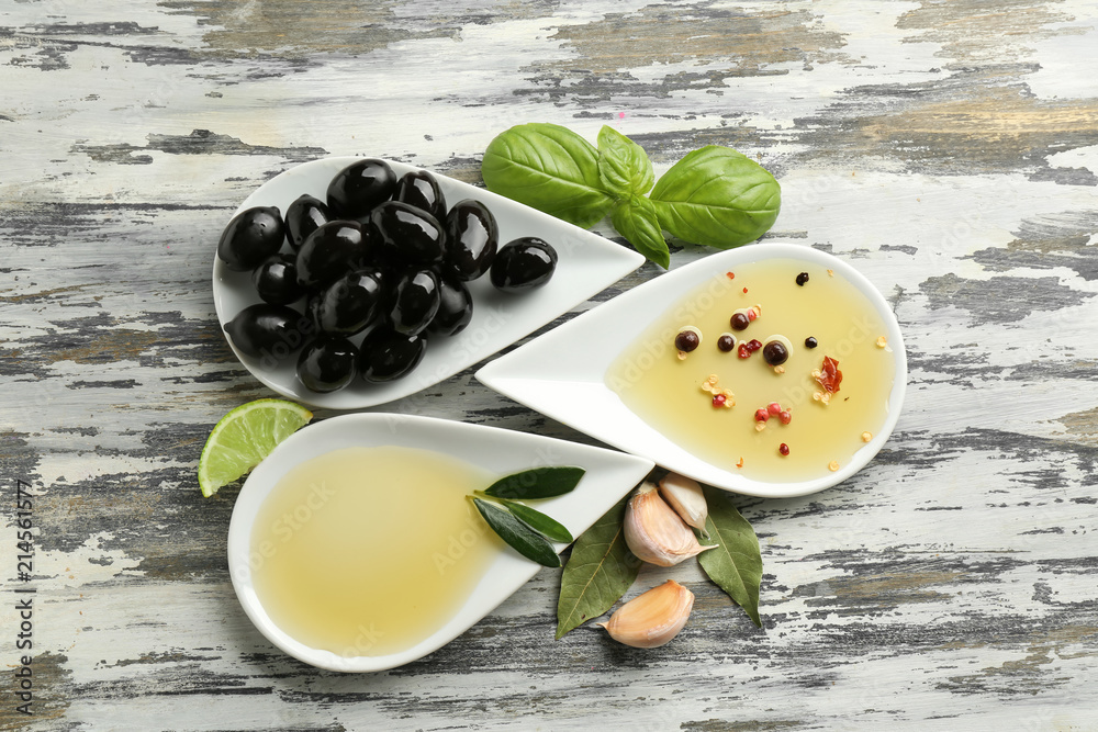 Plates with oil and olives on table