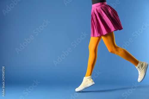 Fotografía Legs of beautiful young woman wearing tights and skirt on color background