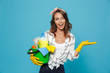 Portrait of smiling happy housewife 20s wearing yellow rubber gloves for hands protection holding bucket with cleaning supplies, isolated over blue background