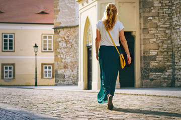 woman wearing pleated skirt and walking in old european city