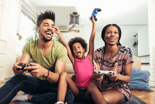 Smiling Family Sitting On The Couch Together Playing Video Games