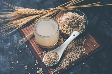 Canvas Print - Barley water in glass with raw and cooked pearl barley wheat/seeds. selective focus