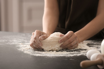 Woman kneading dough on kitchen table