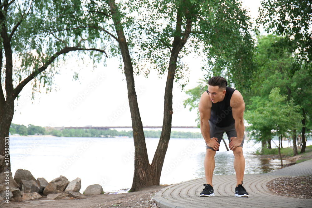 Sporty young man resting after running in park