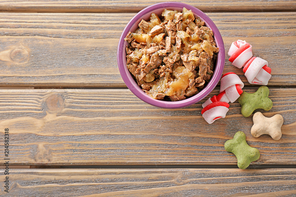 Bowl with pet food on wooden background