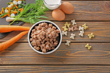 Bowl with pet food and natural products on wooden background