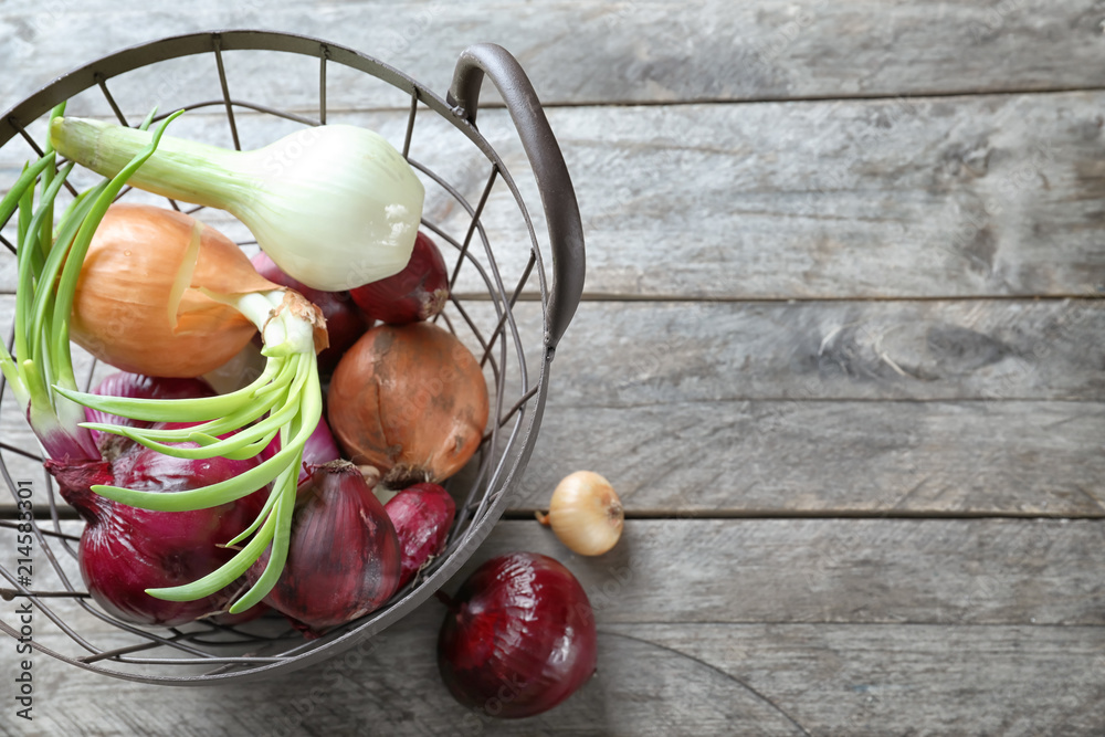 Metal basket with fresh onions on wooden background