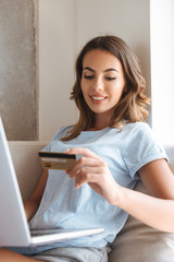 Wall Mural - Smiling young woman holding credit card