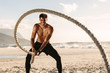 © Jacob Lund - Man doing fitness training at the beach using battling rope