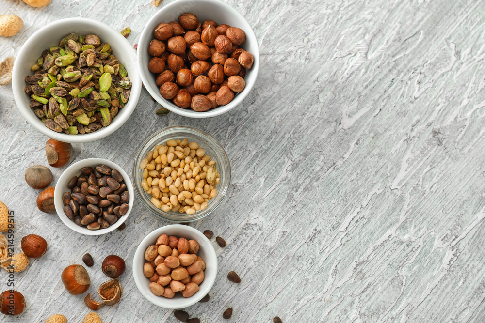 Bowls with different nuts on textured background