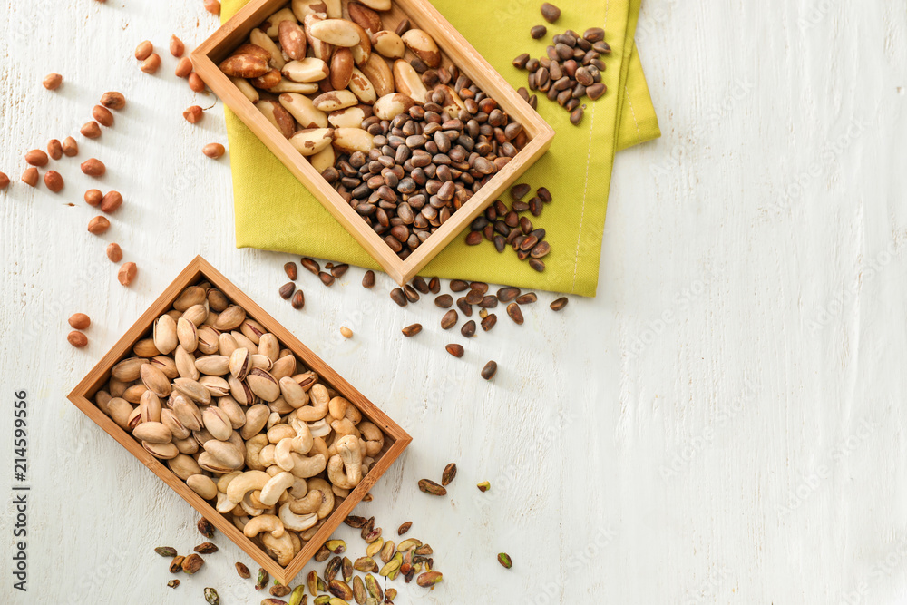 Boxes with different nuts on white wooden background