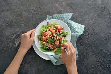 Woman eating tasty quinoa salad at table, closeup