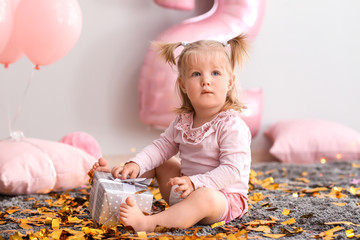 Wall Mural - Cute little girl with gift box sitting on carpet in room decorated for birthday party