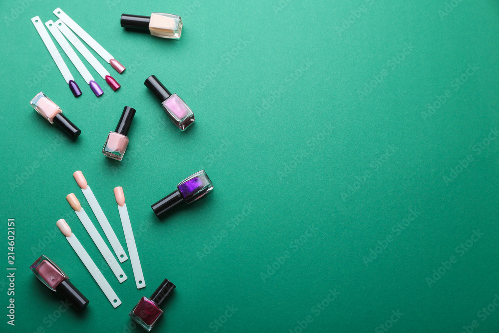Bottles of varnish and artificial nails on color background
