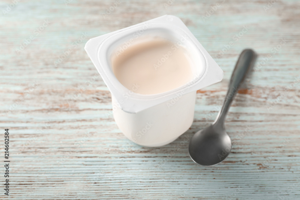 Plastic cup with yummy yogurt on wooden background