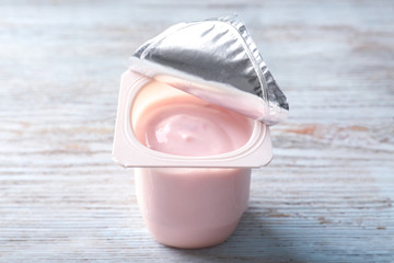 Plastic cup with yummy strawberry yogurt on wooden background