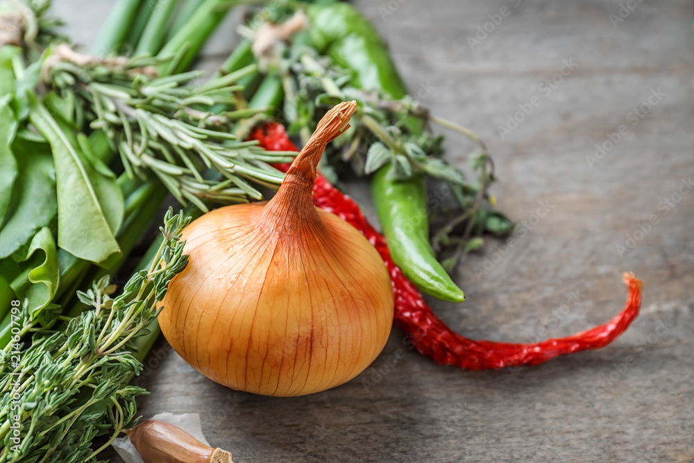 Fresh herbs with vegetables on wooden background