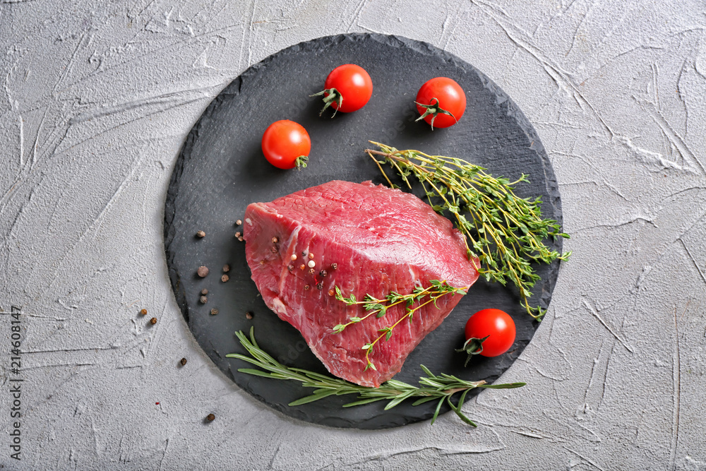 Fresh raw meat with spices and herbs on slate plate
