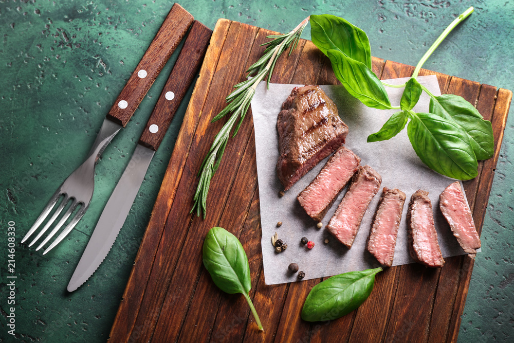 Cut grilled meat with herbs and spices on wooden board