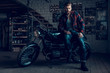 © VadimGuzhva - Bearded Biker Sitting on Motorcycle in Garage.