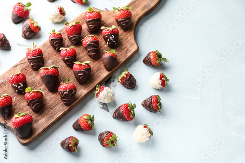 Fotomural Wooden board with delicious strawberries covered with chocolate on color backgro
