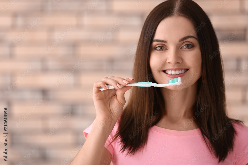 Young woman brushing her teeth on blurred background