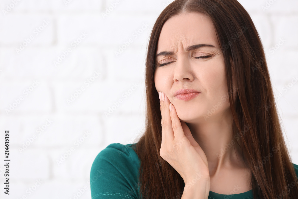 Young woman suffering from toothache on blurred background