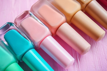 Bottles of colorful nail polishes on wooden background