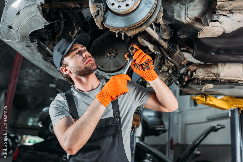 mechanic repairing car without wheel in workshop