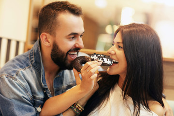 Wall Mural - Romantic couple dating in cafe and eating donut